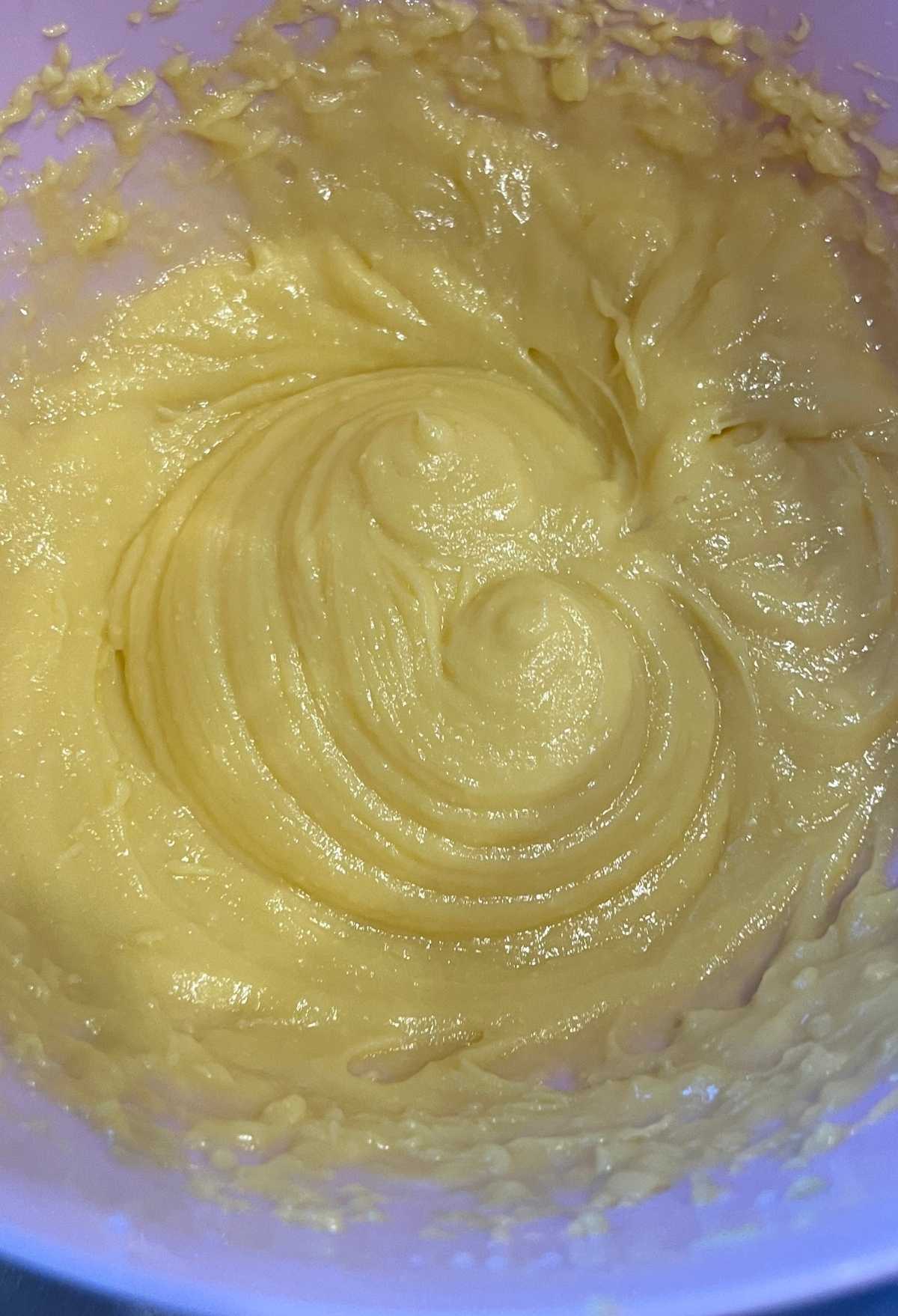 A bowl of yellow eggnog batter with swirls in it.