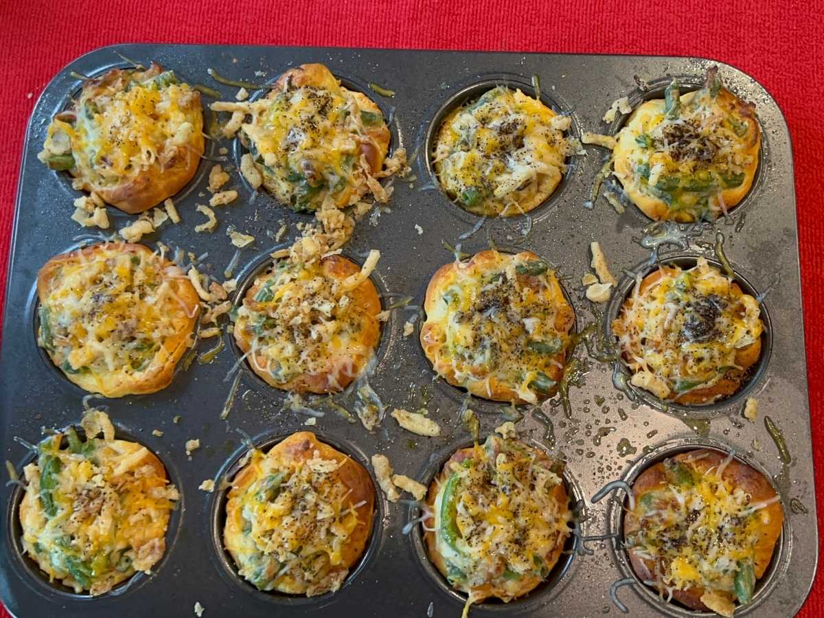 A muffin tin filled with cheesy green bean casserole bites.