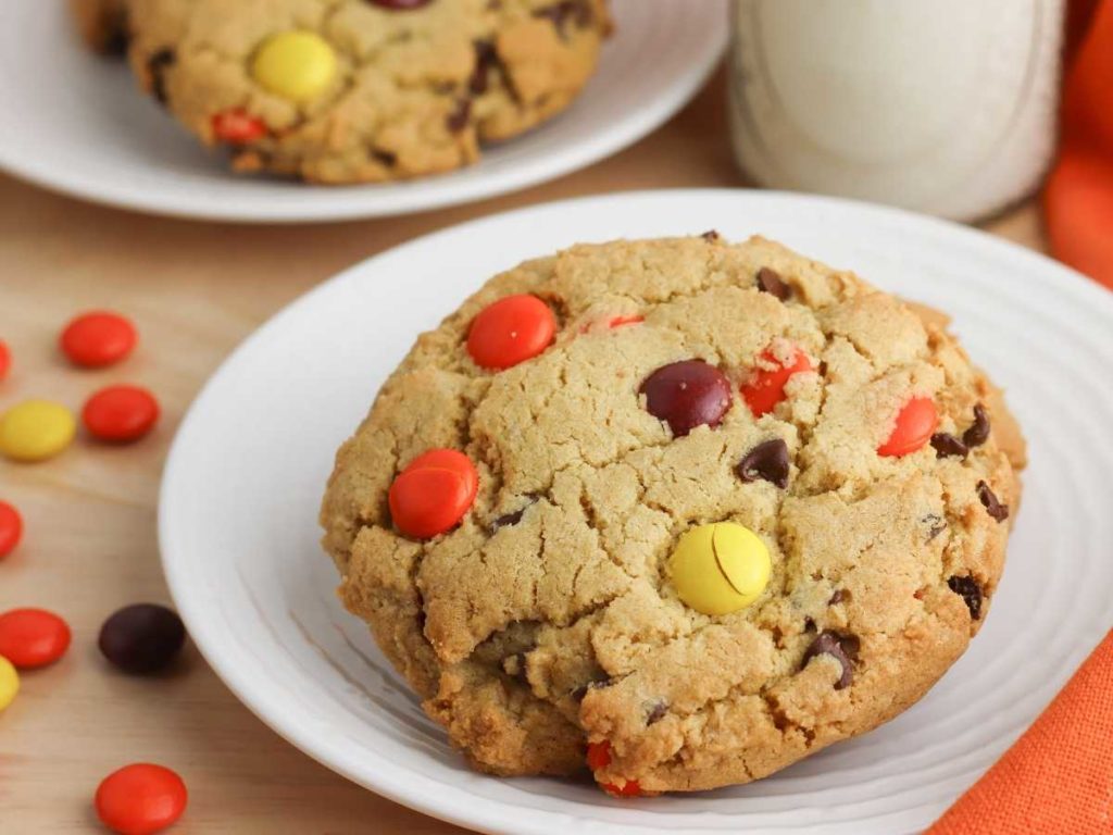 M&m cookies on a plate next to a glass of milk.