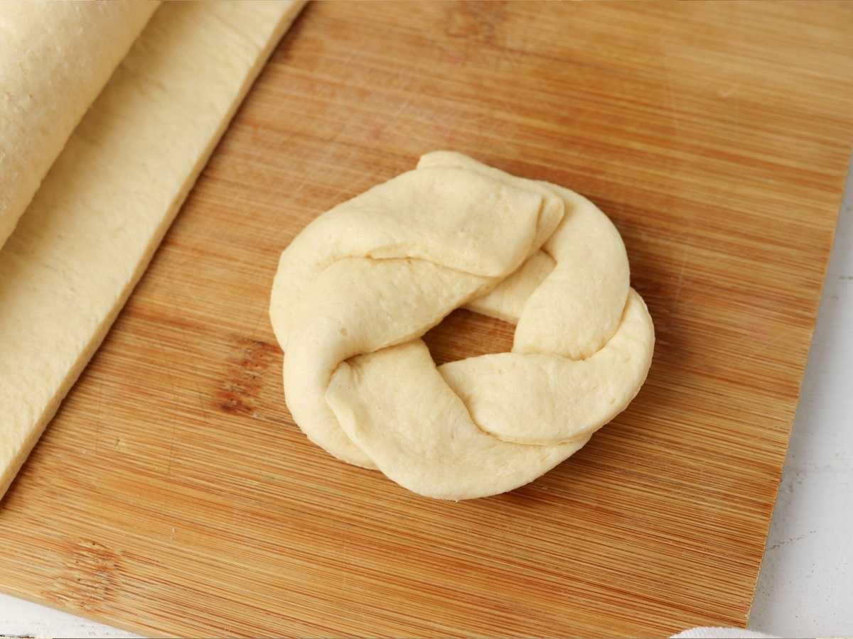 A loaf of dough on a cutting board ready to be shaped into crescent rolls.