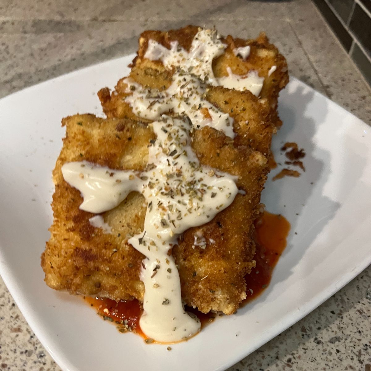 A plate topped with a piece of bread with lasagna fritta sauce on it.