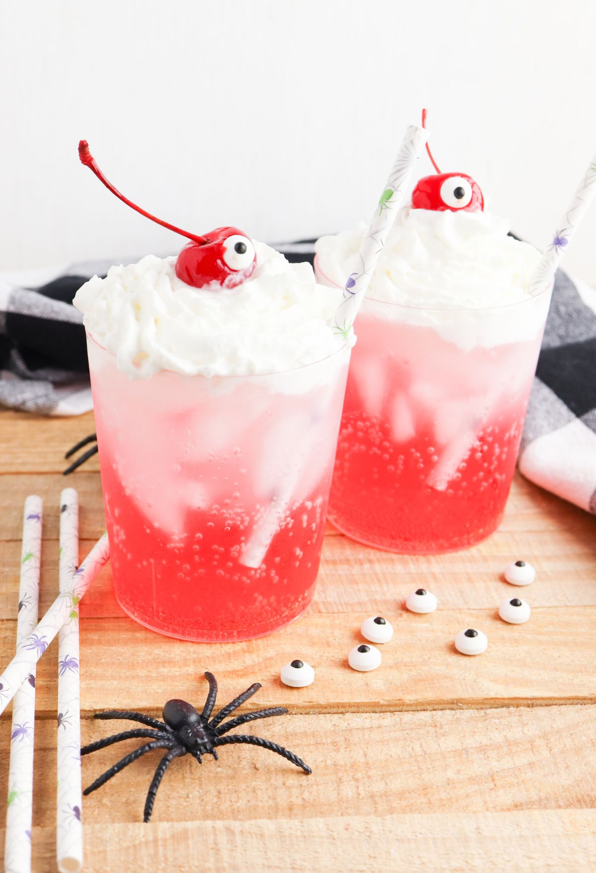 Two glasses with whipped cream and spiders on top.
