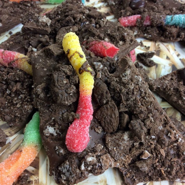 A chocolate bark covered in gummy worms and candy.