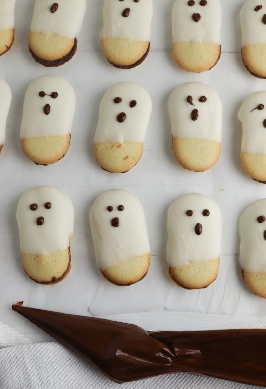 Ghost cookies on a baking sheet with icing and a knife.