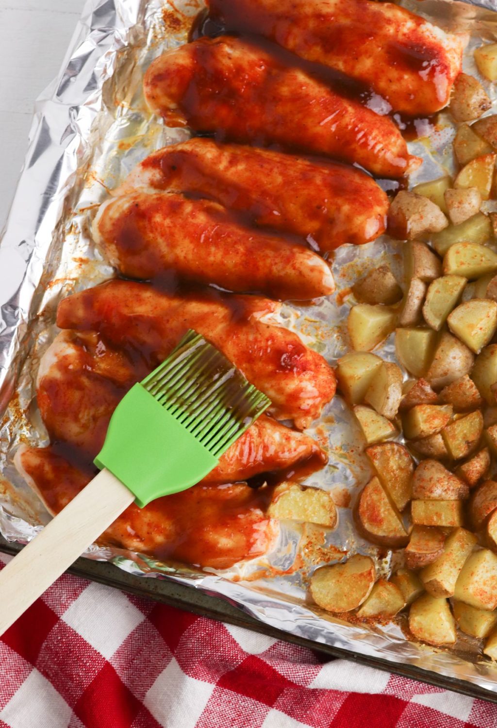 Bbq chicken and potatoes on a baking sheet.