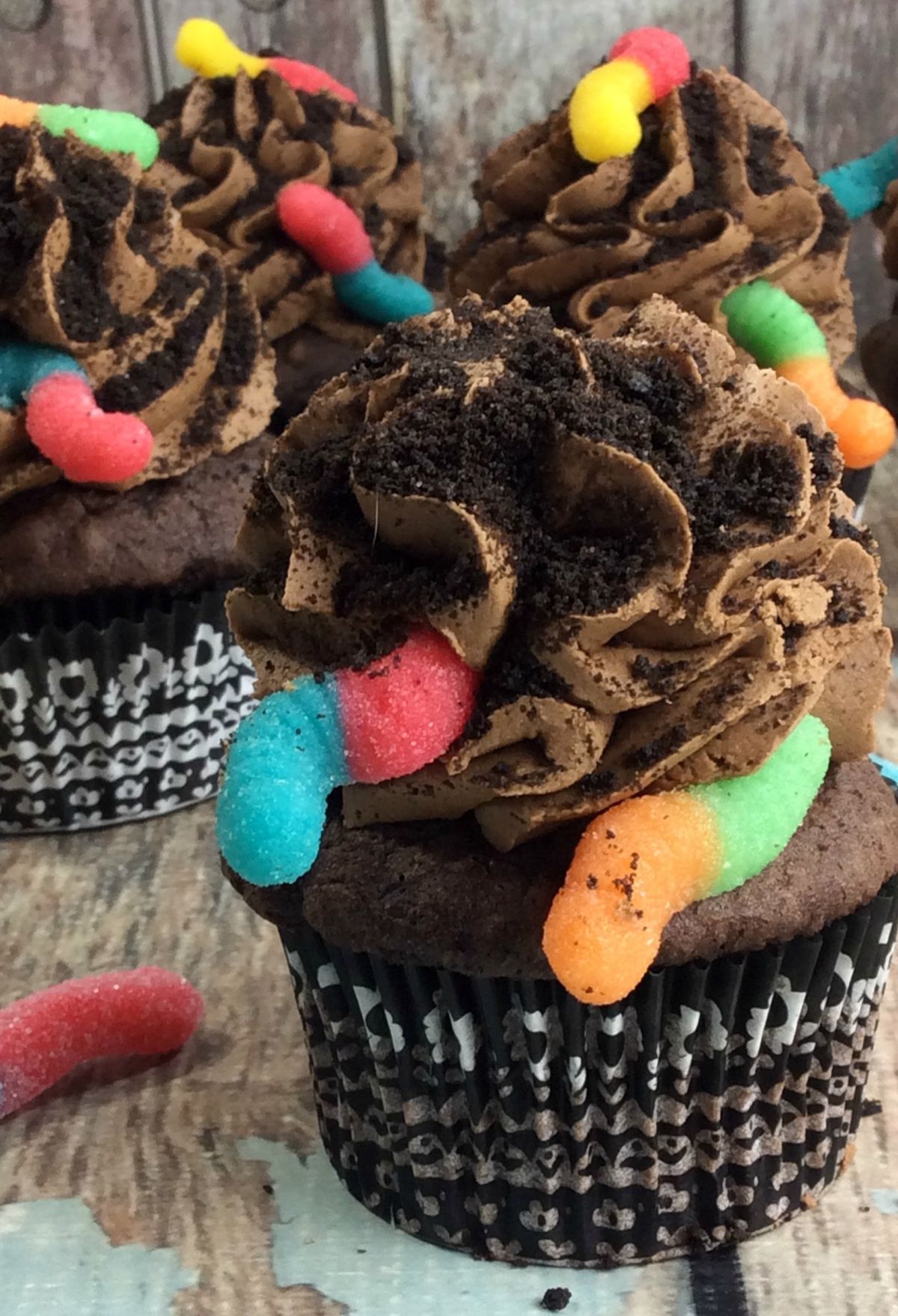 Chocolate cupcakes with gummy worms on top.