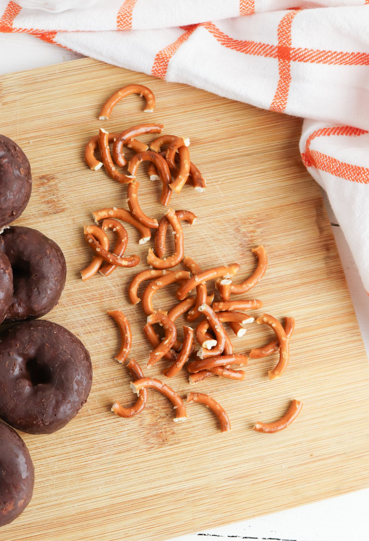 Chocolate pretzel doughnuts on a cutting board.