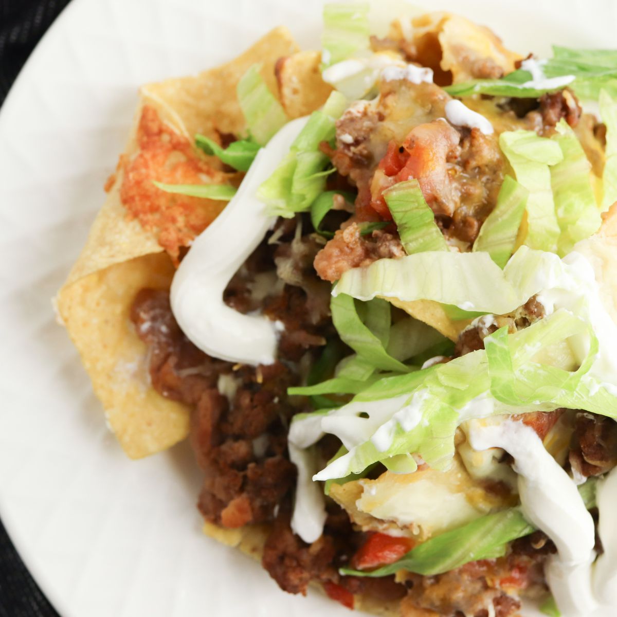 A plate topped with nachos and sour cream.