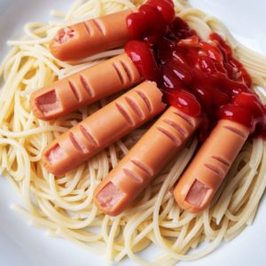 A plate of spaghetti with hot dogs and ketchup on it.
