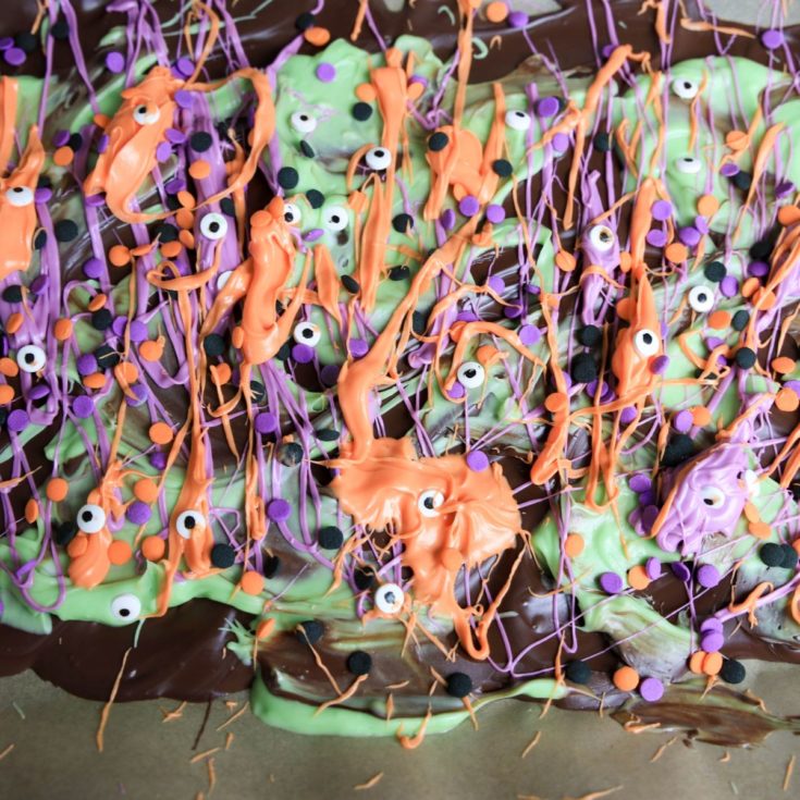 A chocolate bar covered in green, purple, and orange sprinkles.