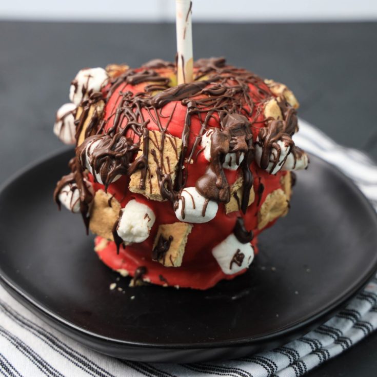 A red apple covered in chocolate and marshmallows.