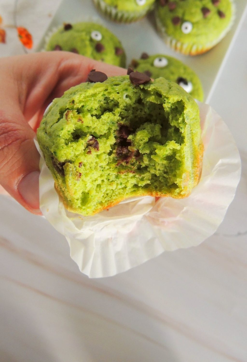 A person holding up a green monster muffin.