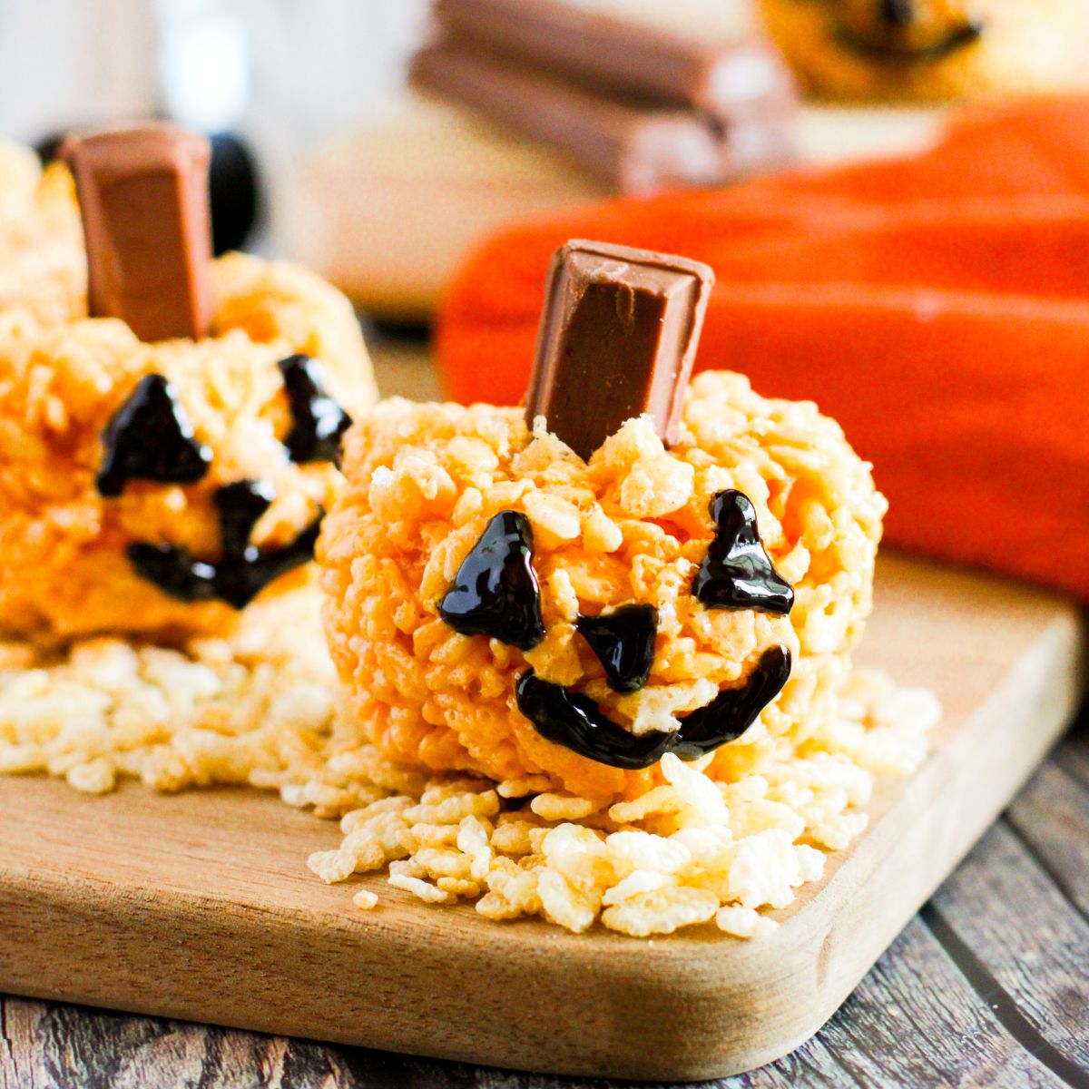 A tray of pumpkin shaped rice krispies on a cutting board.
