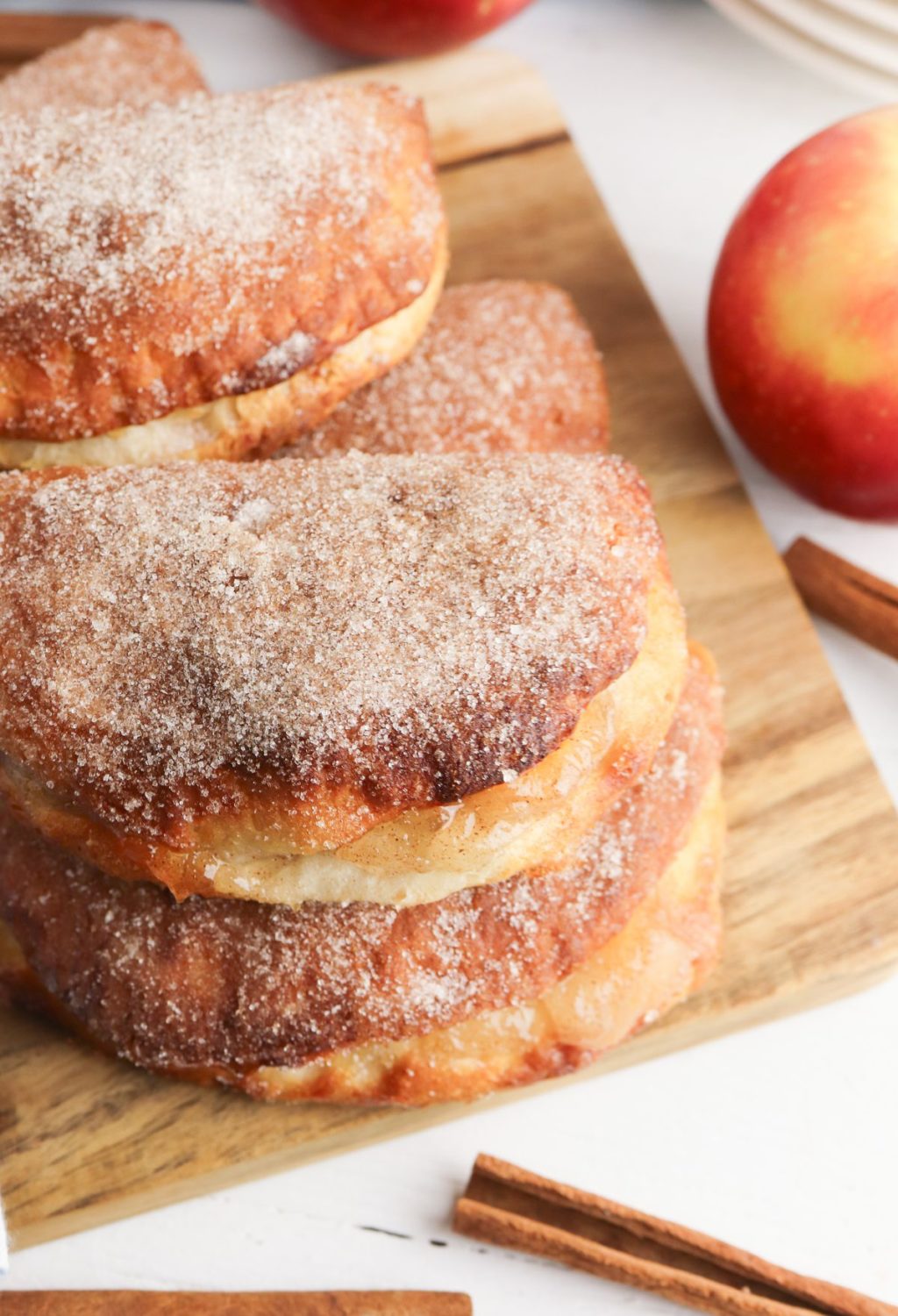 A stack of cinnamon apple donuts on a cutting board.
