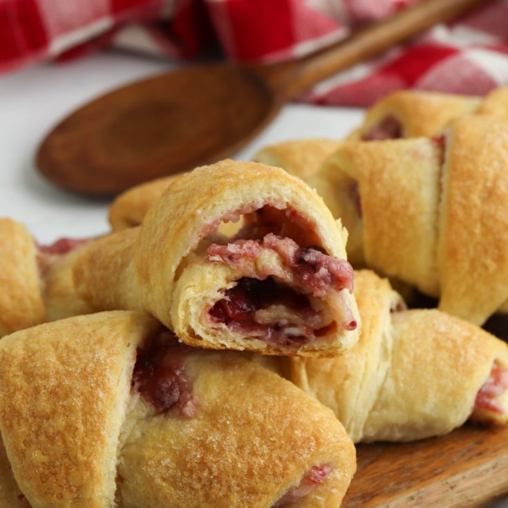 Cranberry cream cheese crescent rolls on a wooden cutting board.