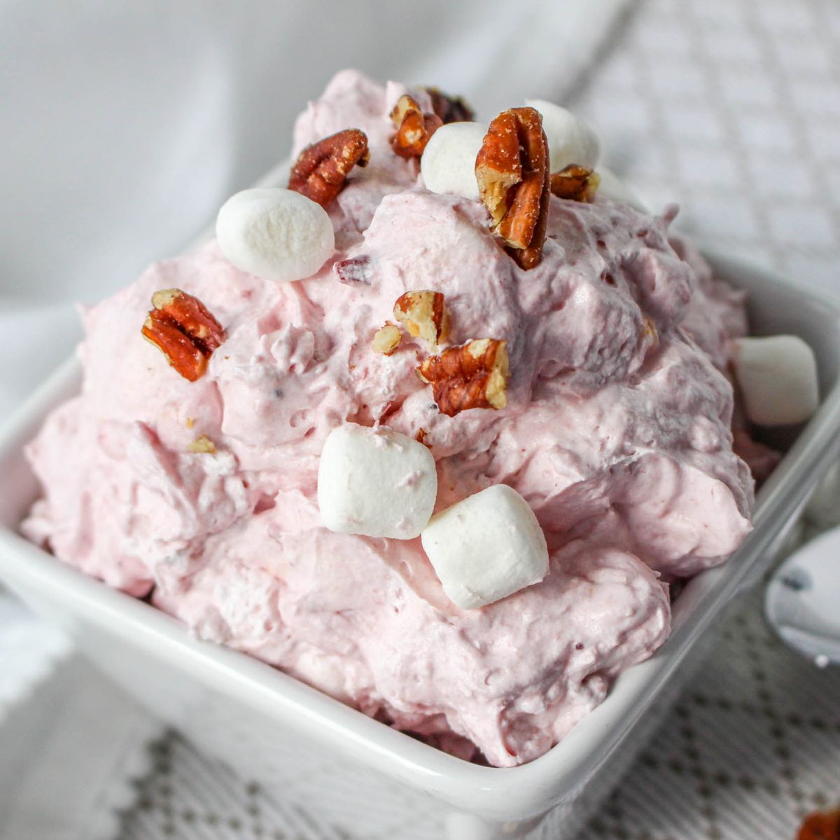 Pink FLUFF with marshmallows and pecans in a white bowl.