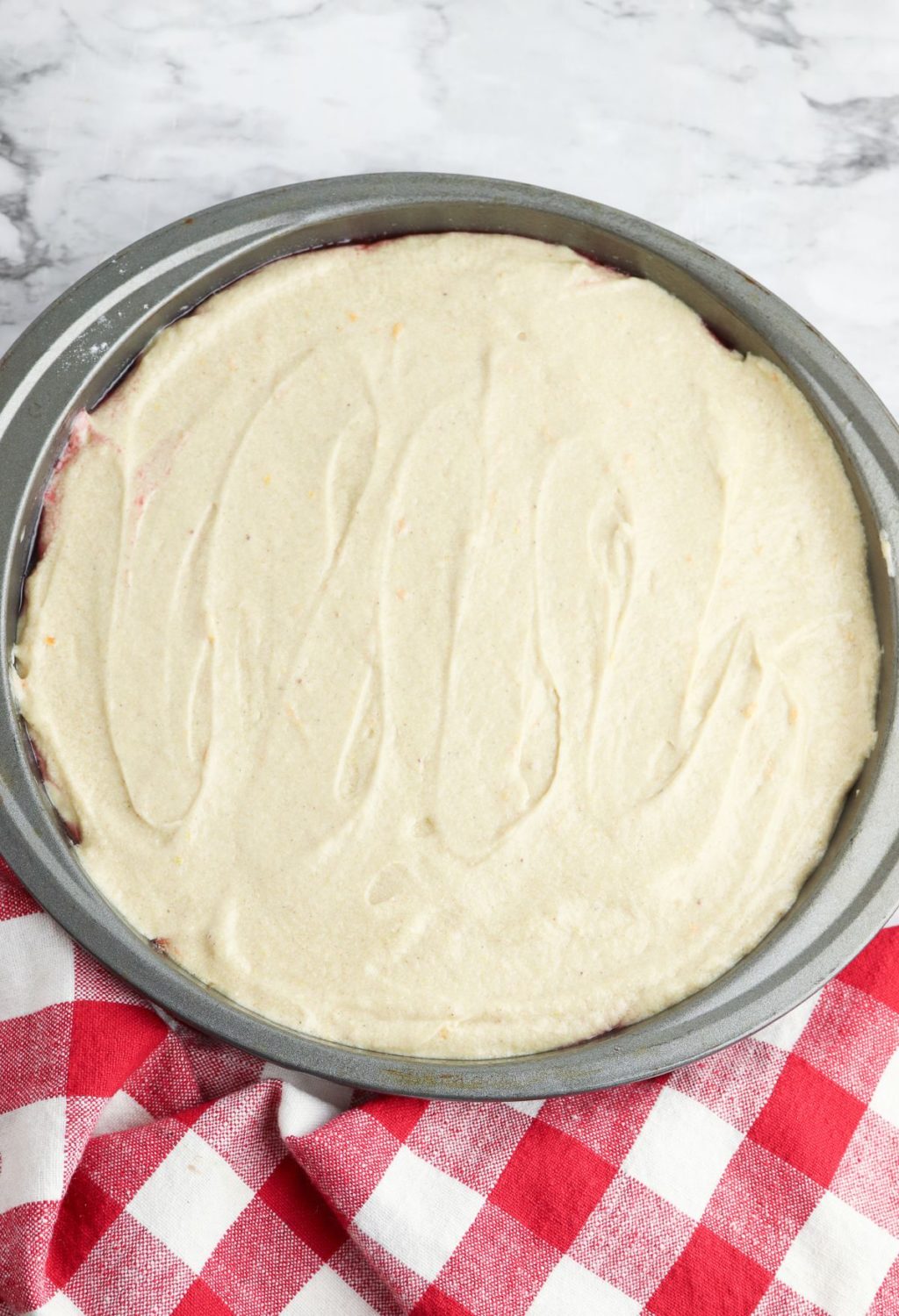 A pie in a pan on a red and white checkered tablecloth.
