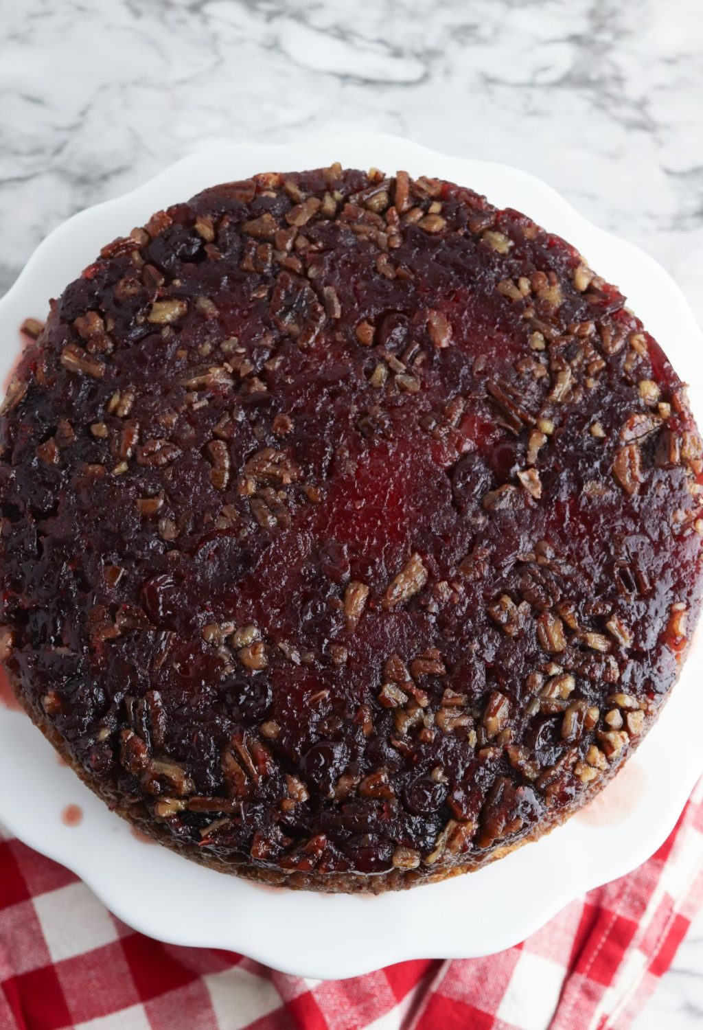 A cranberry pecan cake on a plate with a checkered tablecloth.