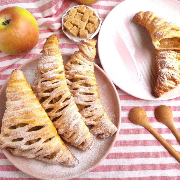 A plate of pastries with apples and a spoon.