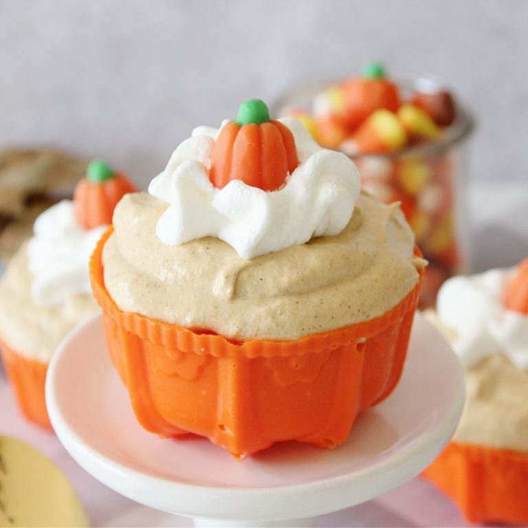 Pumpkin cupcakes topped with whipped cream and candy.