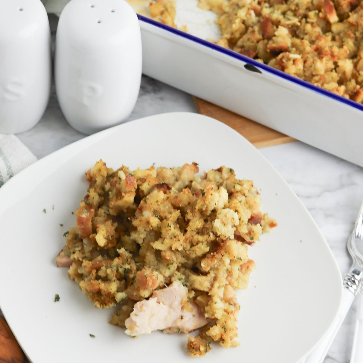 Turkey stuffing on a white plate with salt and pepper shakers.