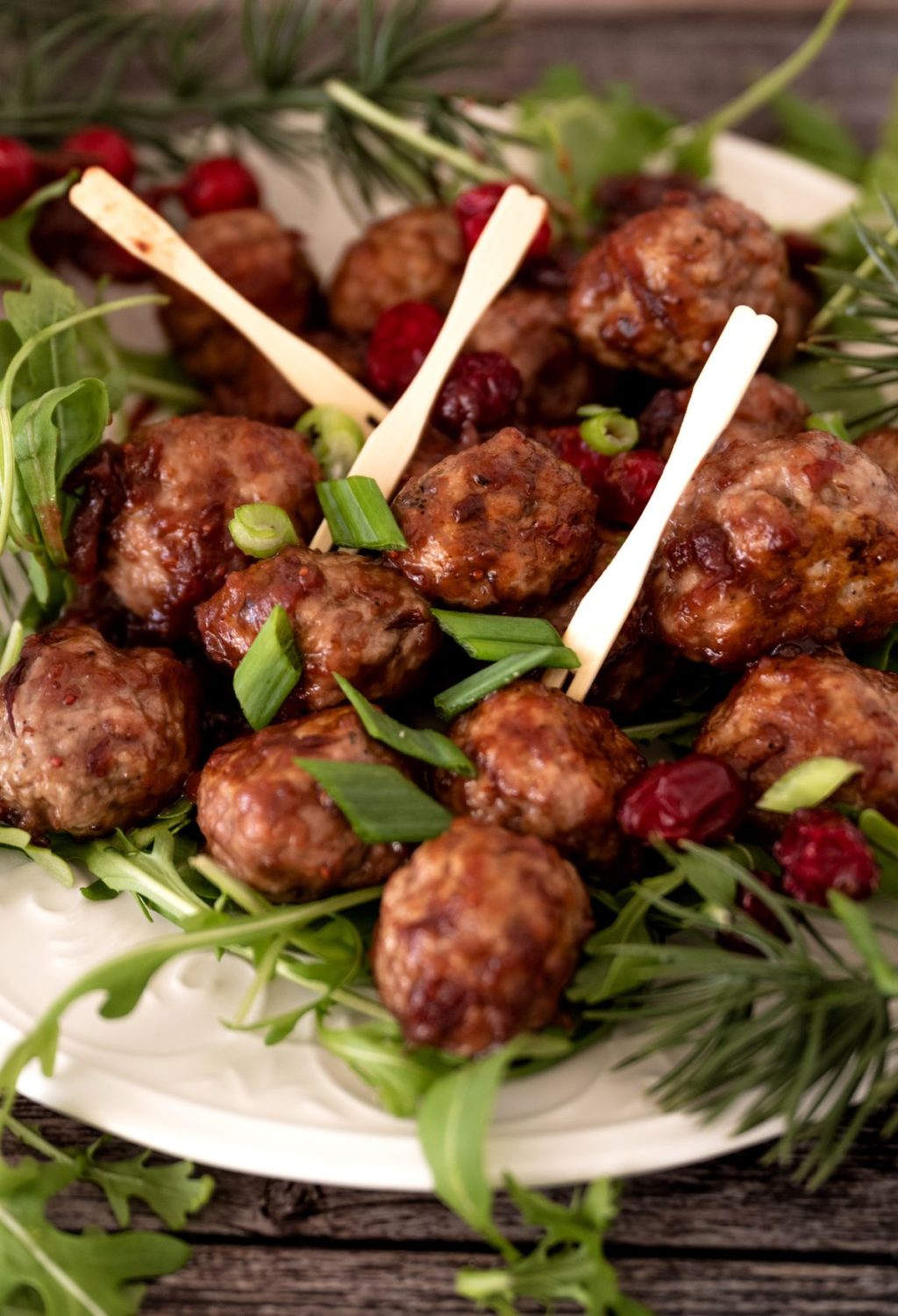 Meatballs with cranberries and greens on a plate.