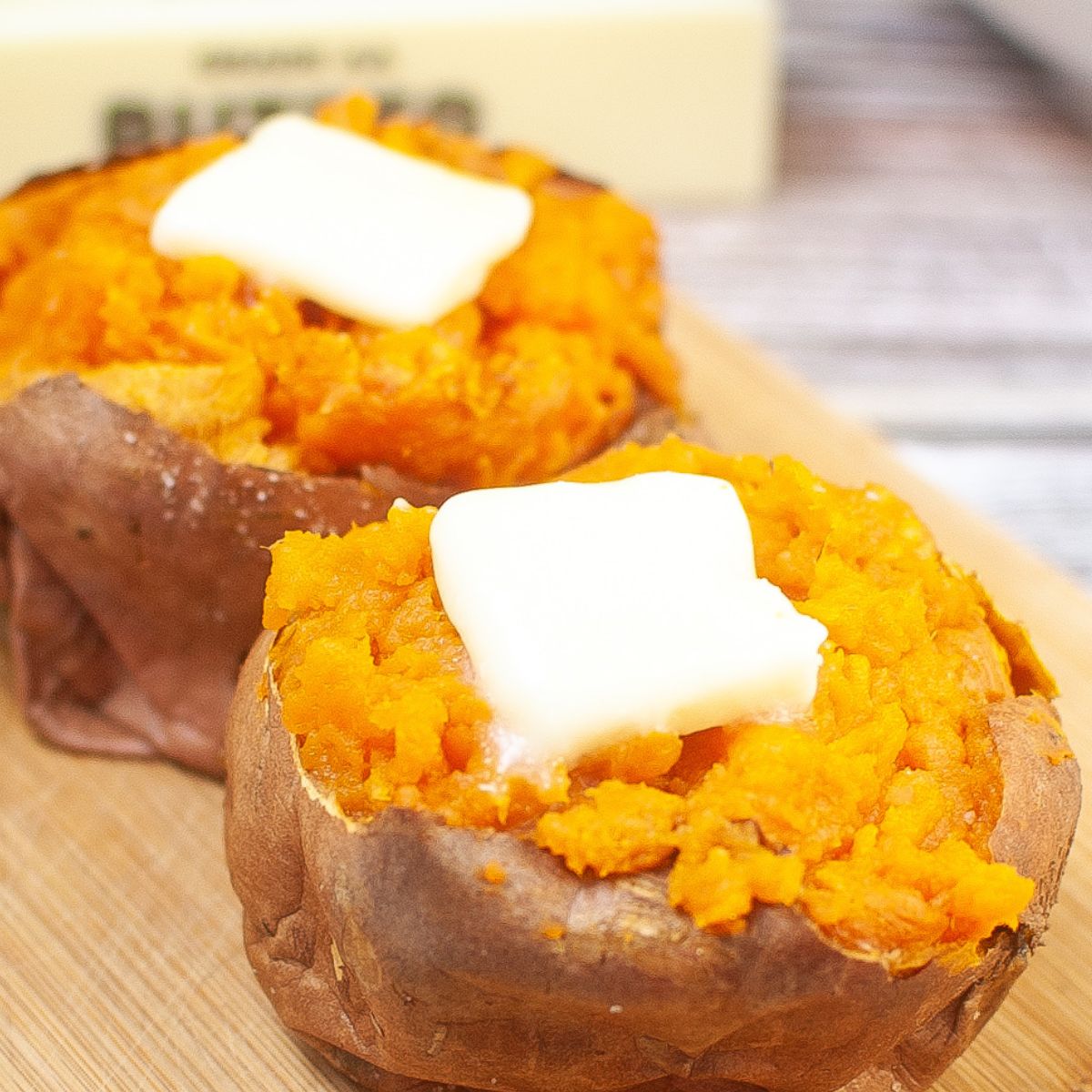 Two baked sweet potatoes on a cutting board.