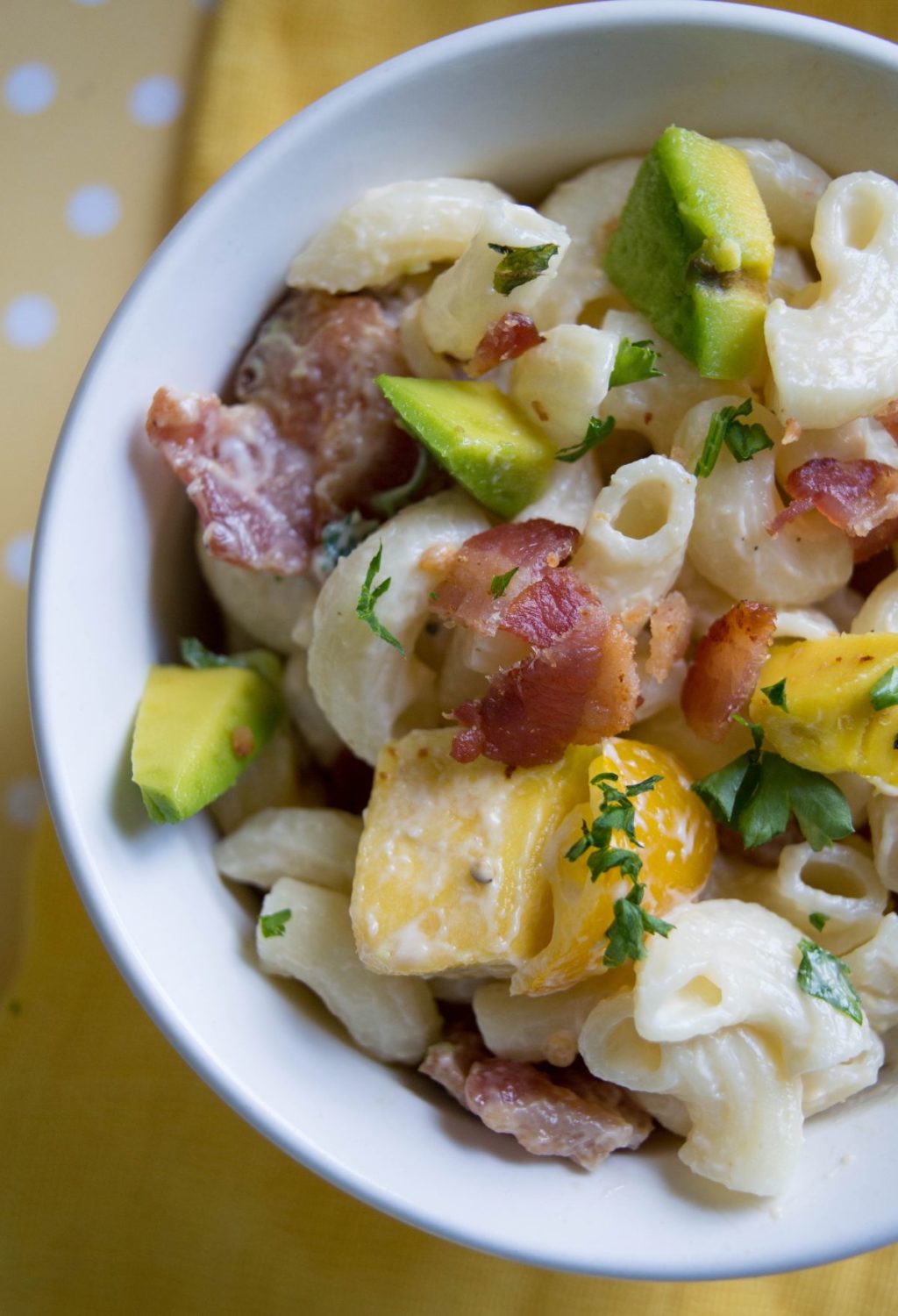 A bowl of pasta with bacon and avocado.