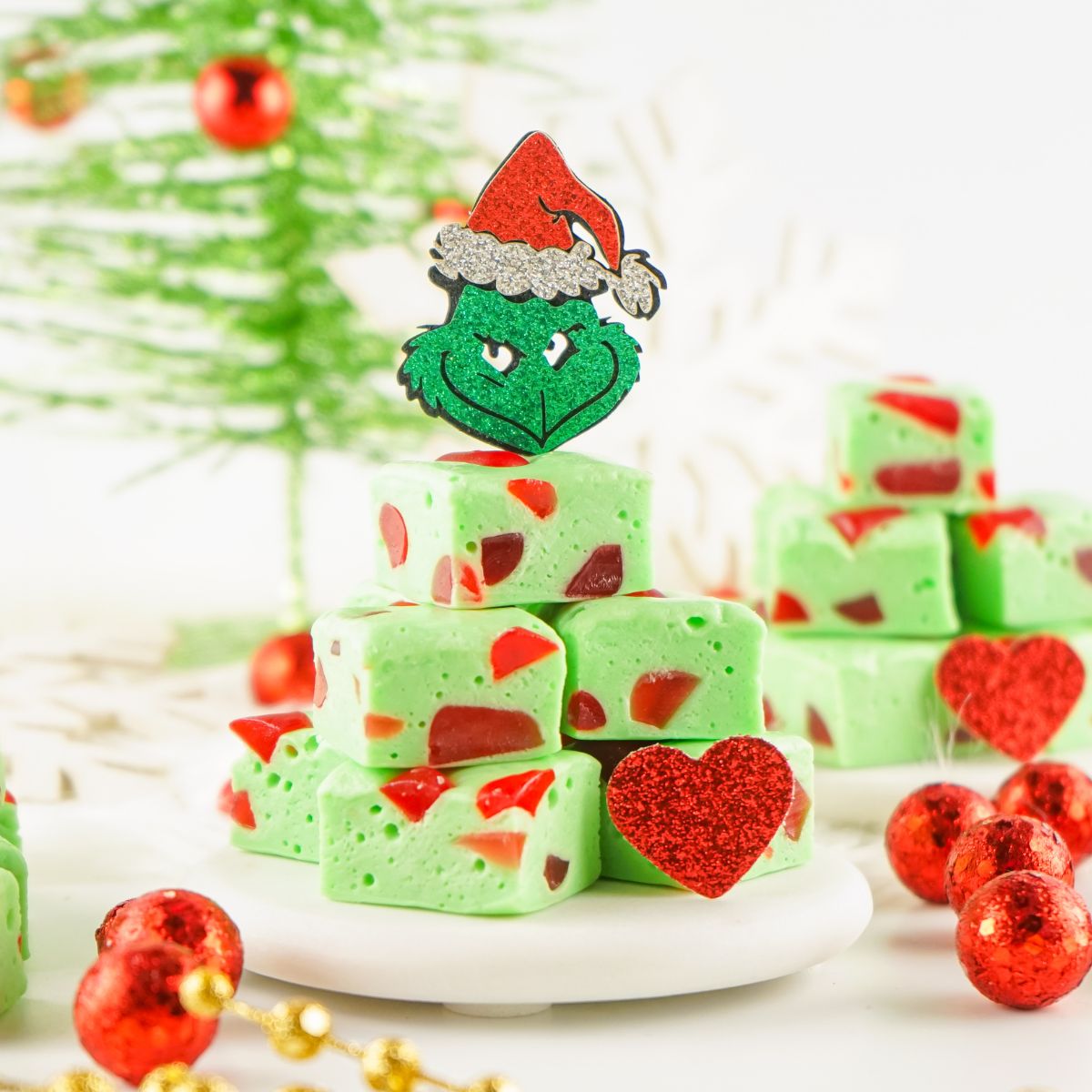 Grinch fudge squares on a plate with christmas decorations.