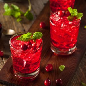 Three glasses of cranberry cocktail on a wooden table.