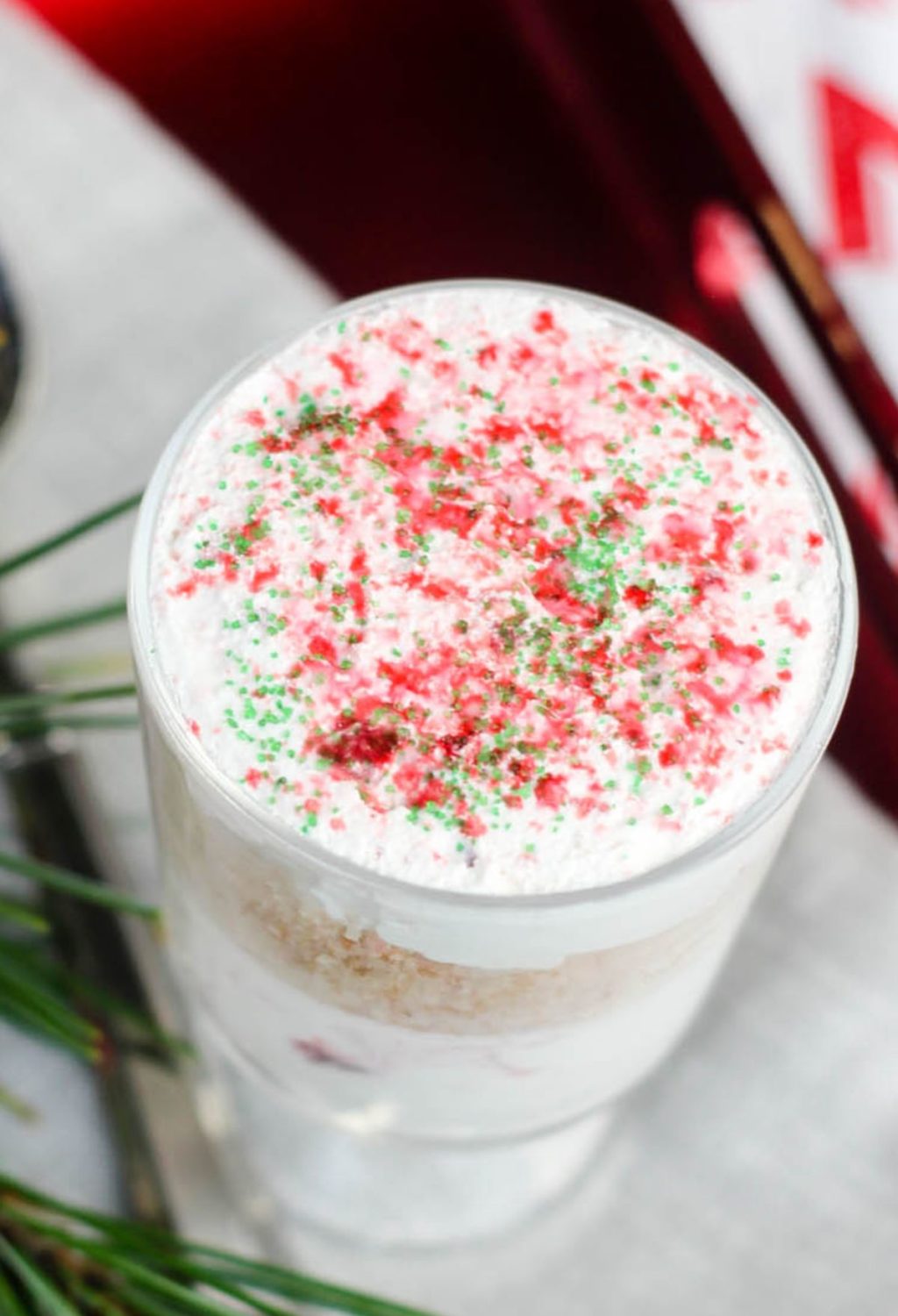 A christmas pudding in a glass with sprinkles on top.