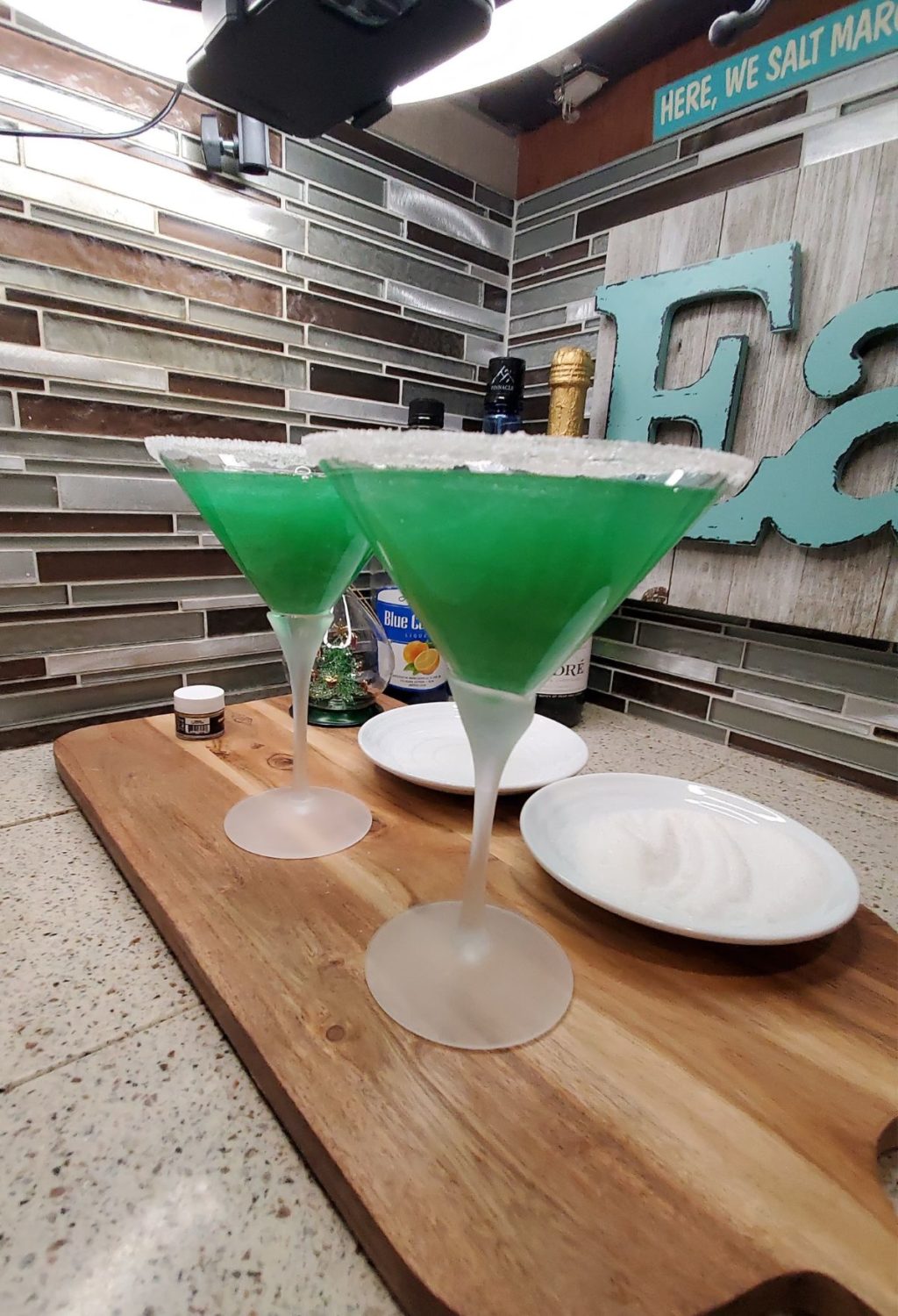 Two green martini glasses on a cutting board.
