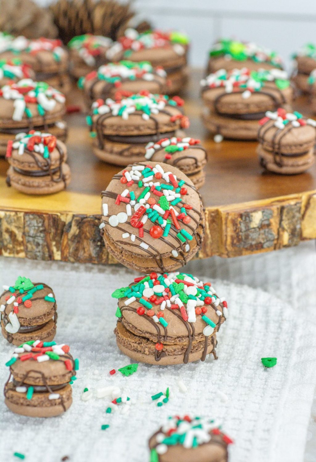 Chocolate macarons with christmas sprinkles on a wooden board.
