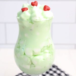 A glass of green christmas fluff dessert dip with hearts on top.