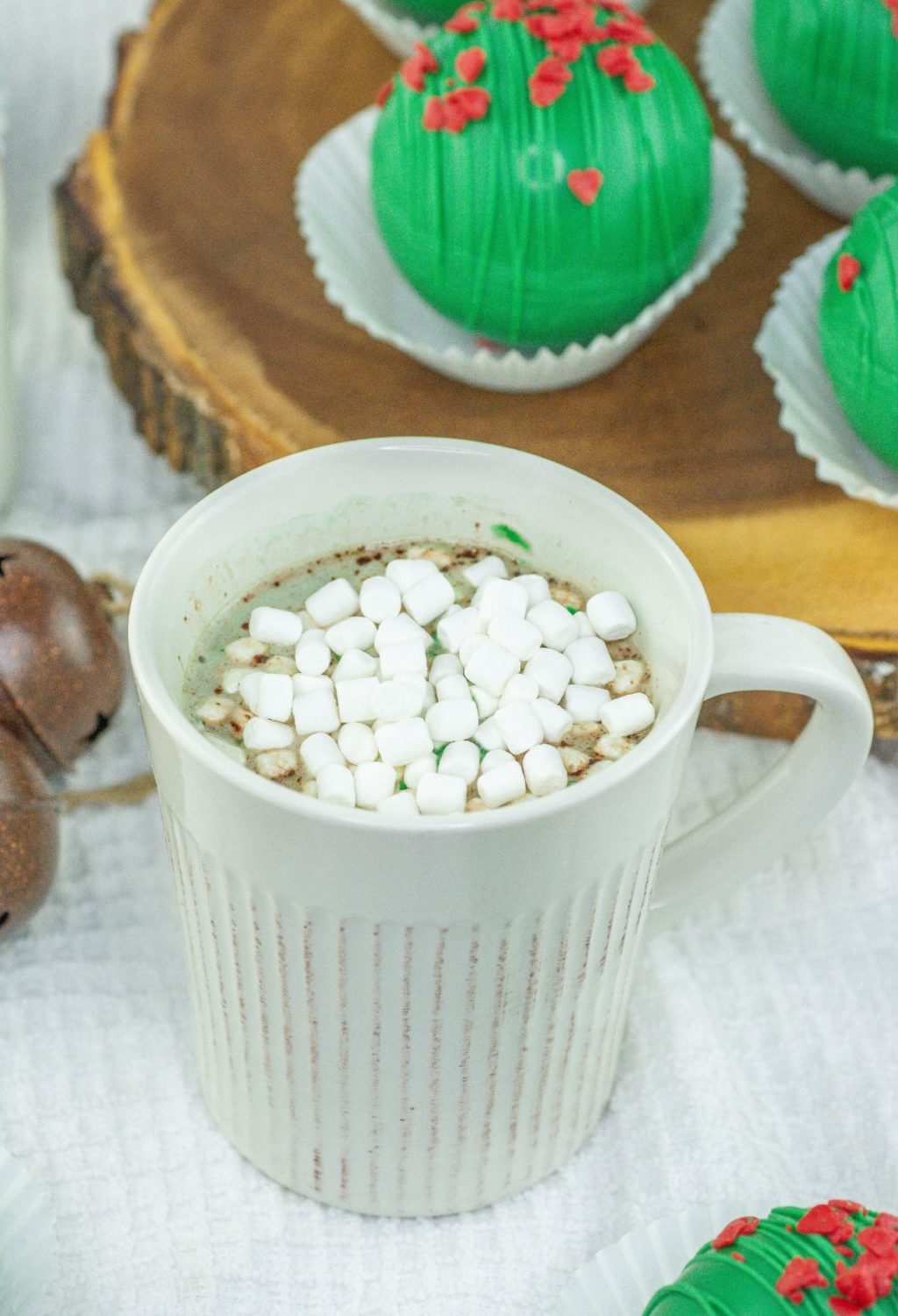 A cup of hot chocolate with marshmallows and green sprinkles.