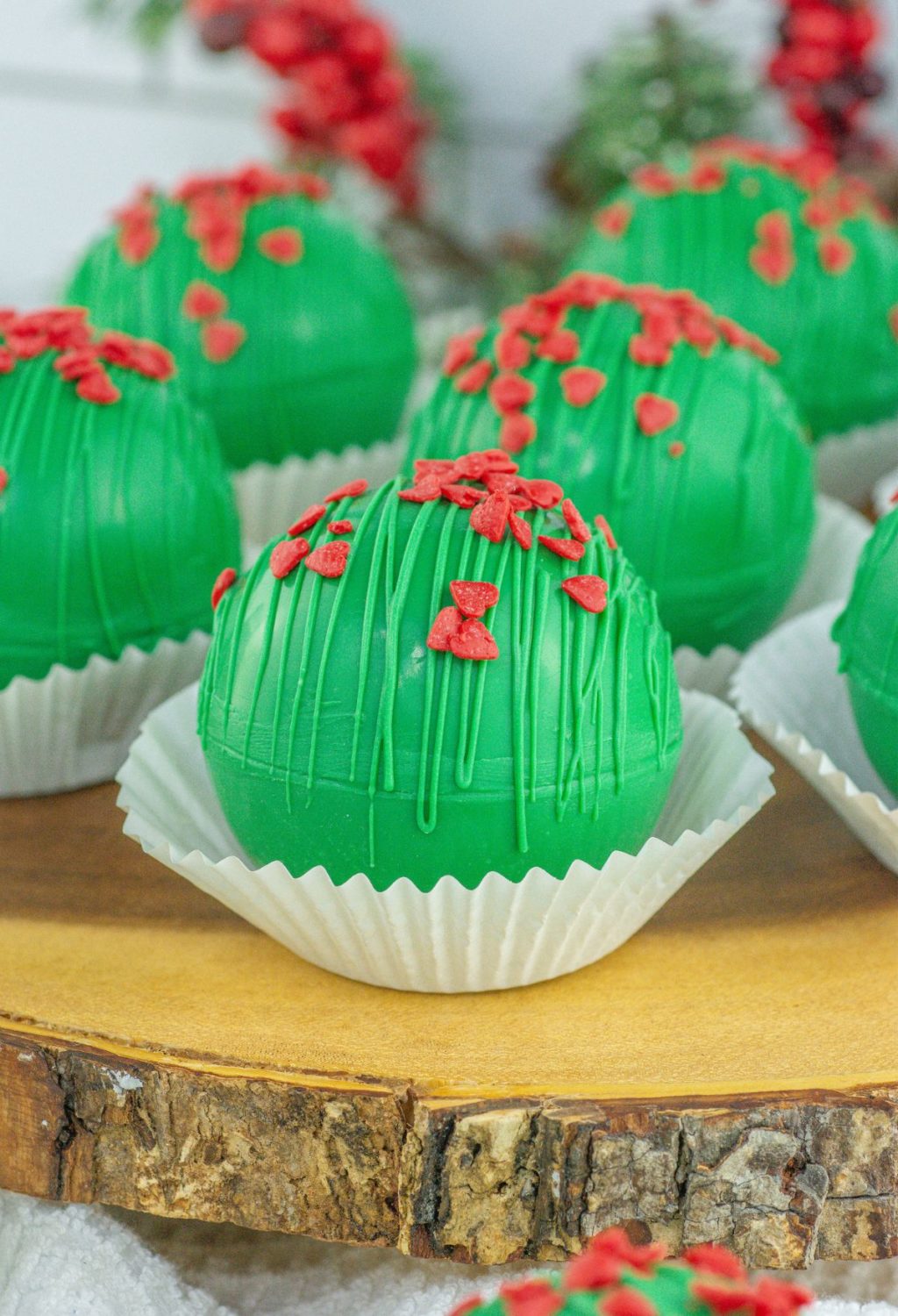 A group of green and red frosted cookies on a wooden board.