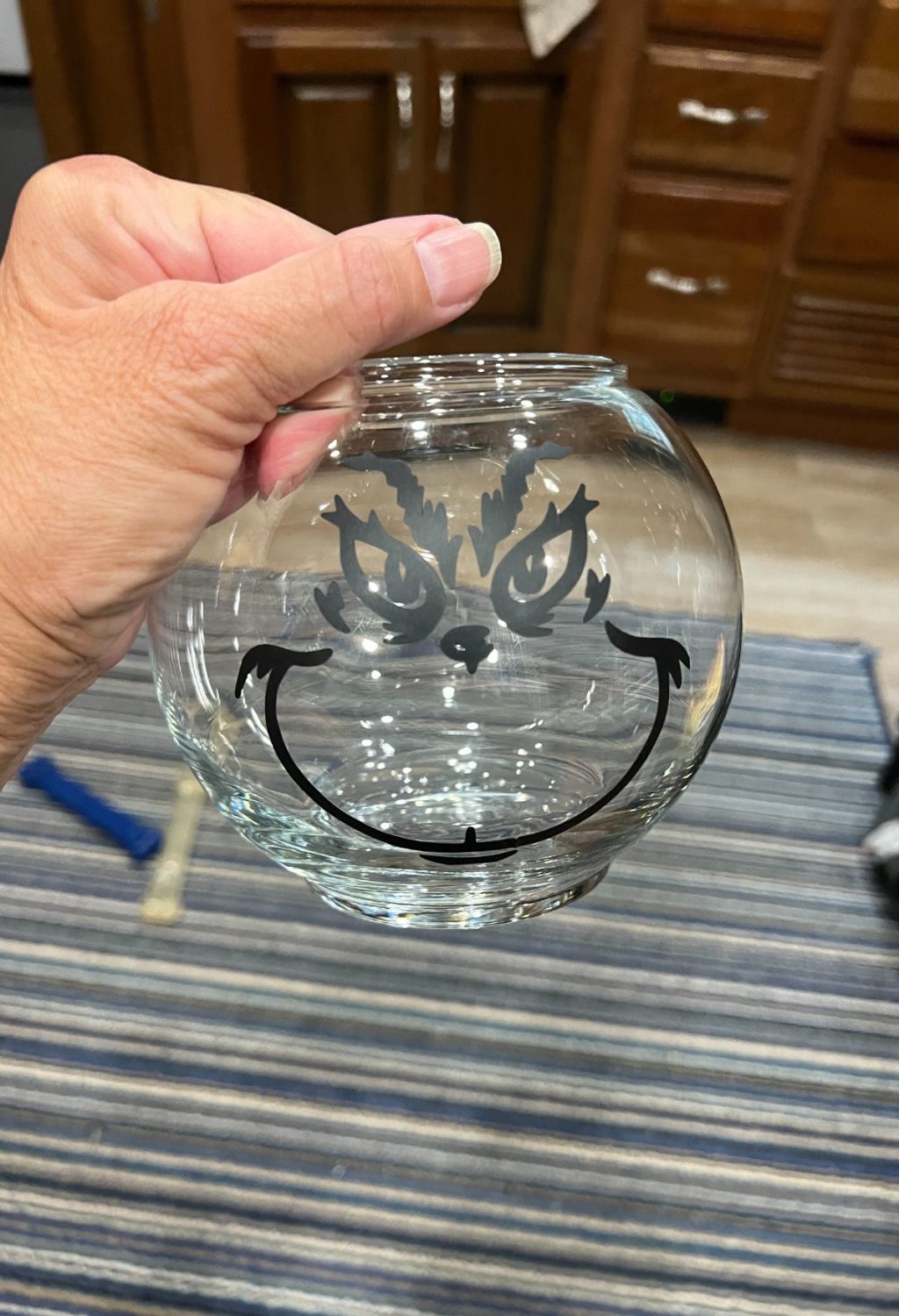 A person holding a glass bowl with a face on it.
