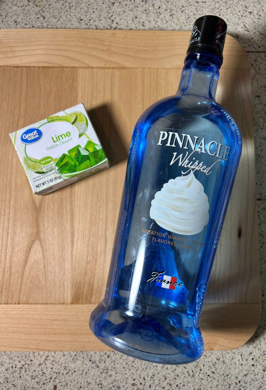 A bottle of vodka and a bar of soap on a cutting board.