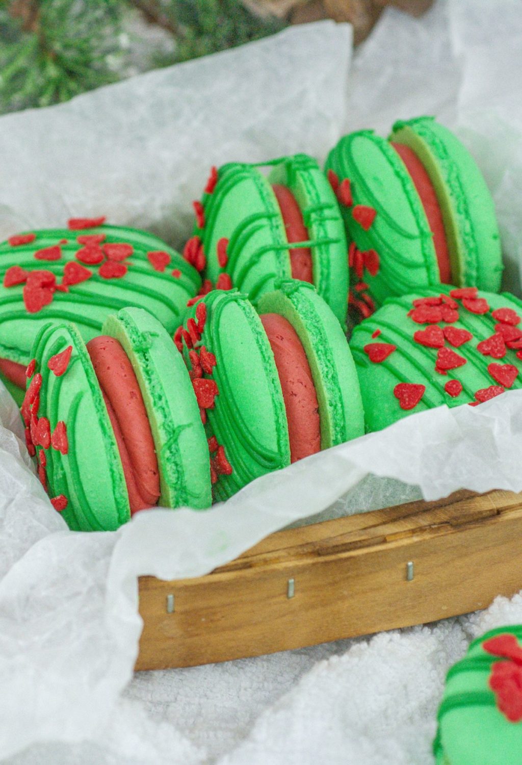 Green and red macarons in a wooden basket.