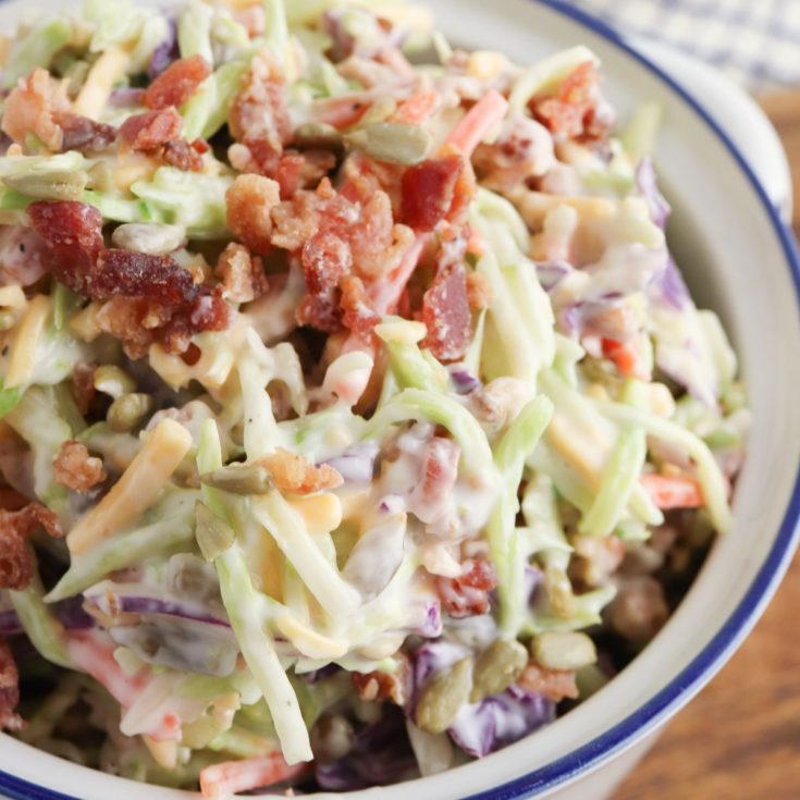 A bowl of coleslaw with bacon and cheese.