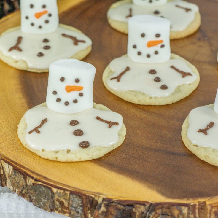 Snowman cookies on a wooden plate.