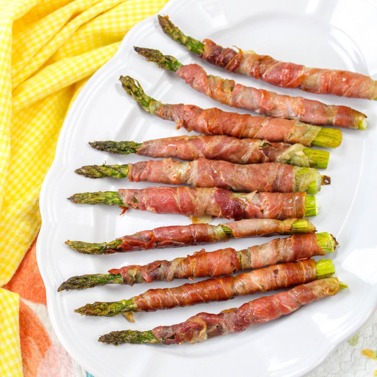 Asparagus wrapped in bacon on a white plate.