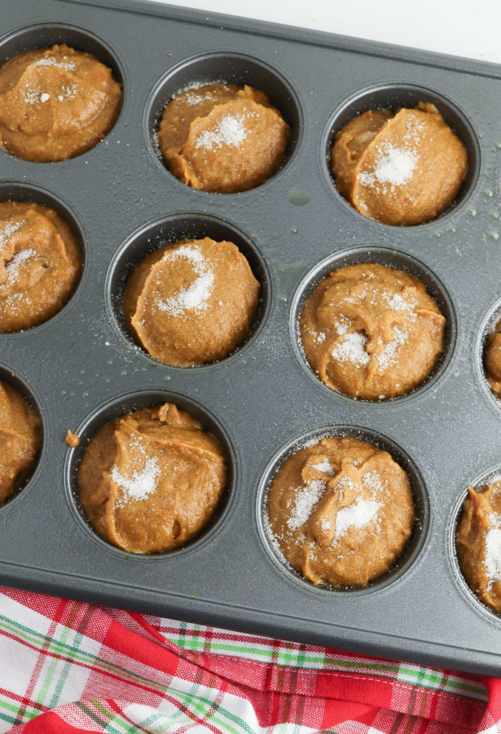 Pumpkin muffins in a muffin tin with powdered sugar.