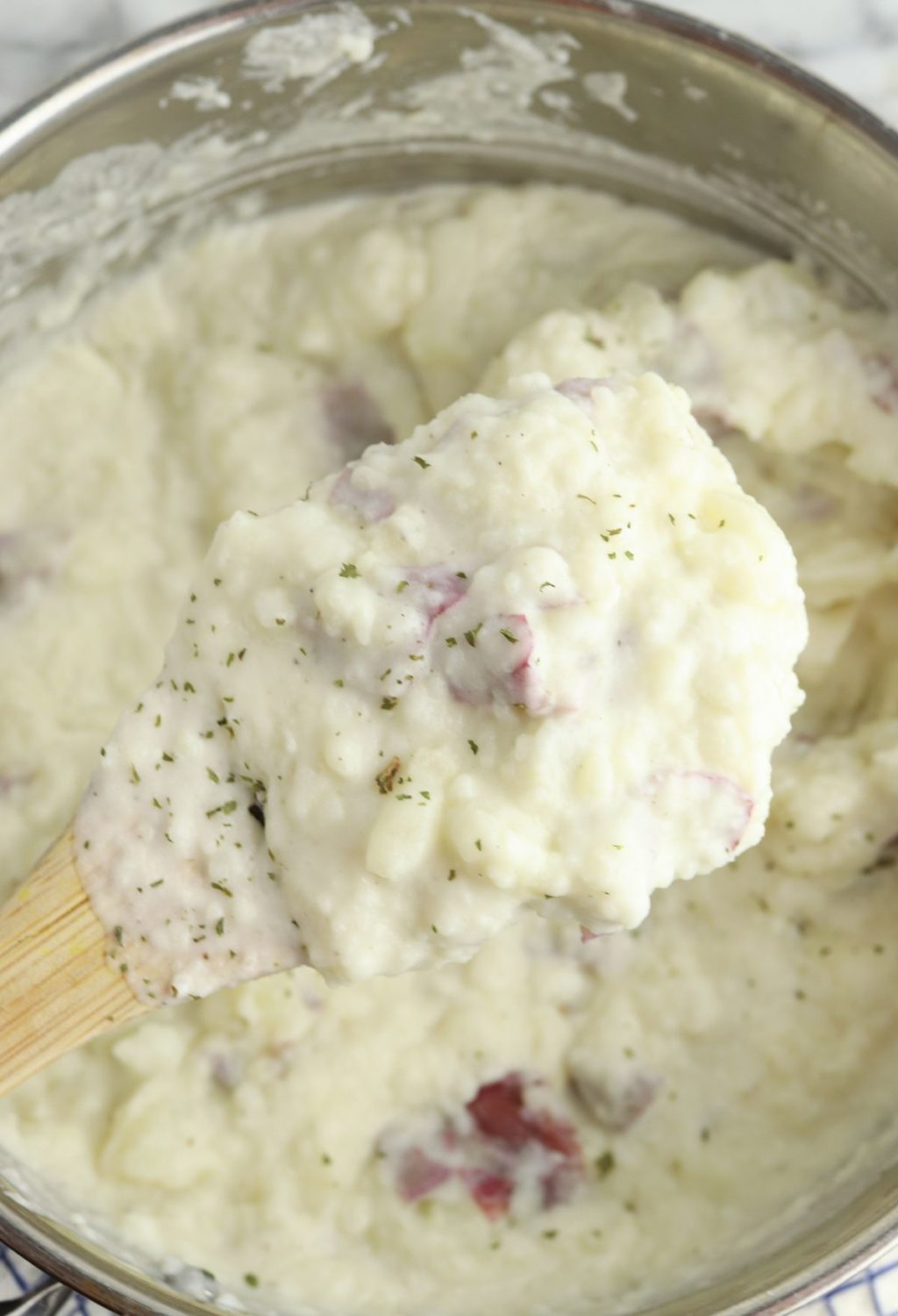 Mashed potatoes in a pan with a wooden spoon.