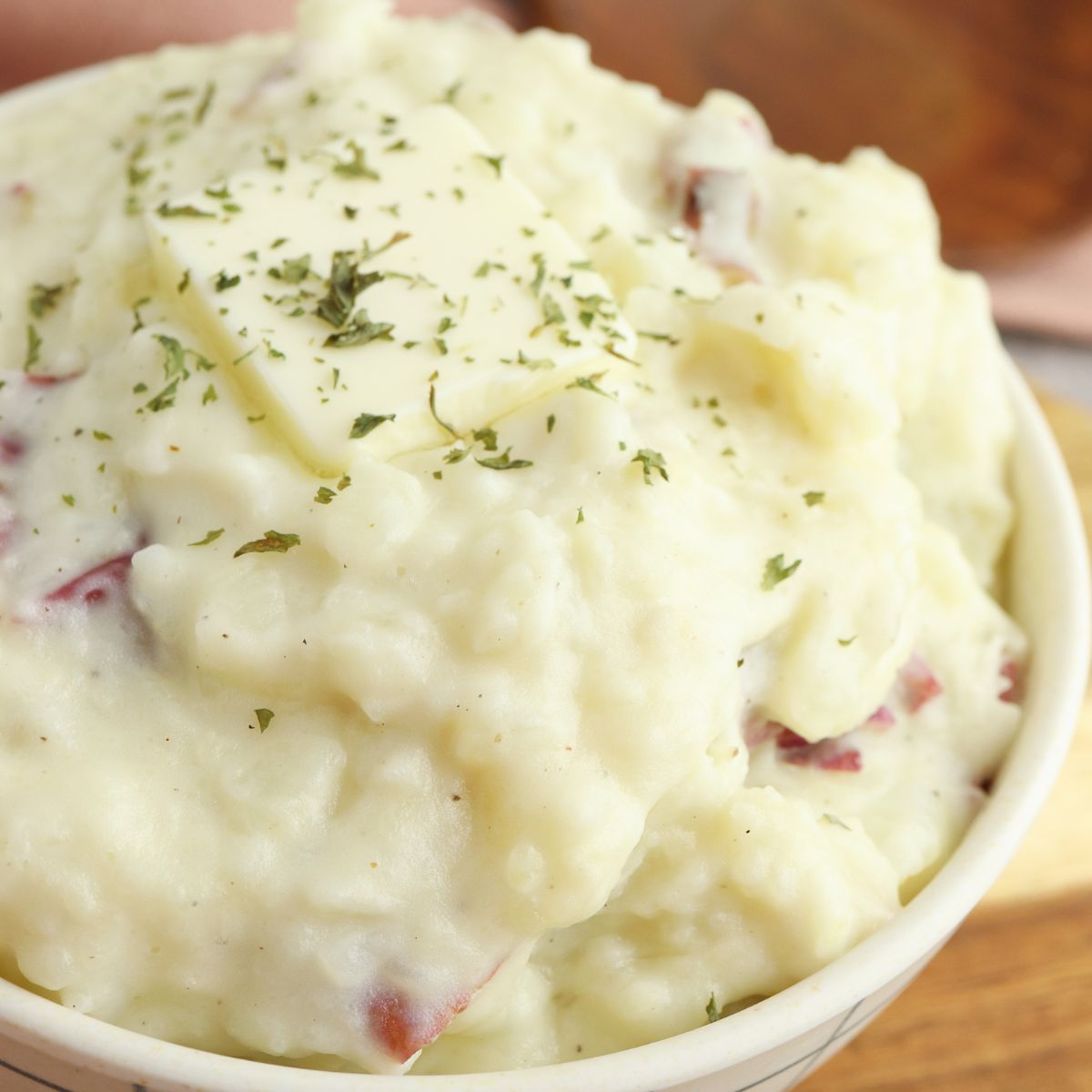 A bowl of mashed potatoes with ham and herbs.