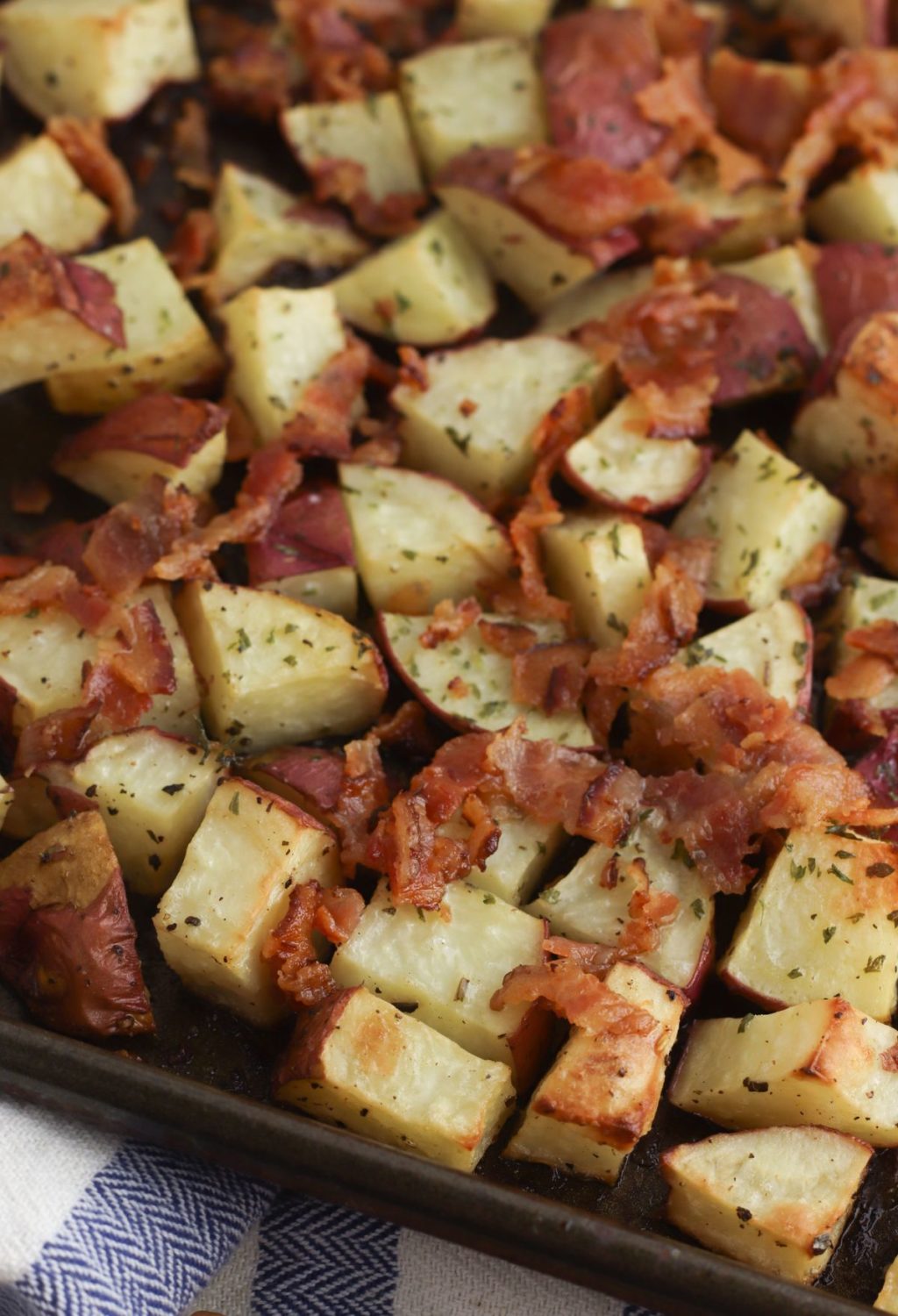 Roasted potatoes with bacon and herbs on a baking sheet.
