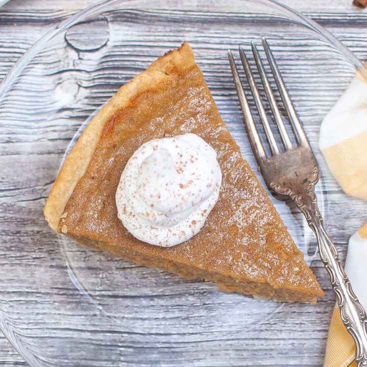 A slice of pumpkin pie with whipped cream on a plate.