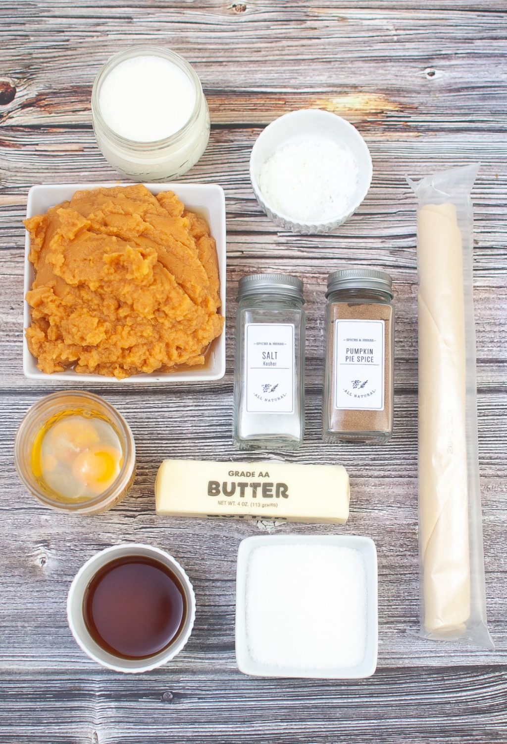 The ingredients for a pumpkin pie are laid out on a wooden table.