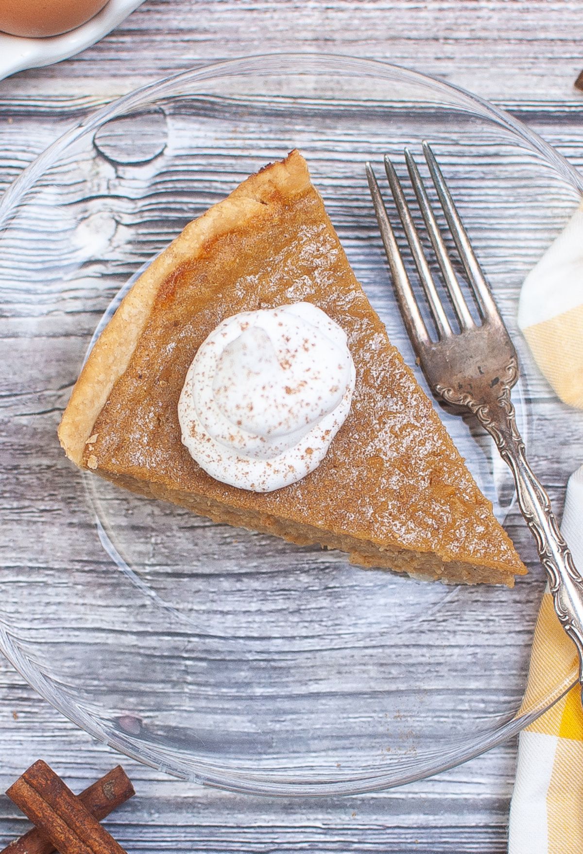 A slice of sweet potato pie with whipped cream on a plate.