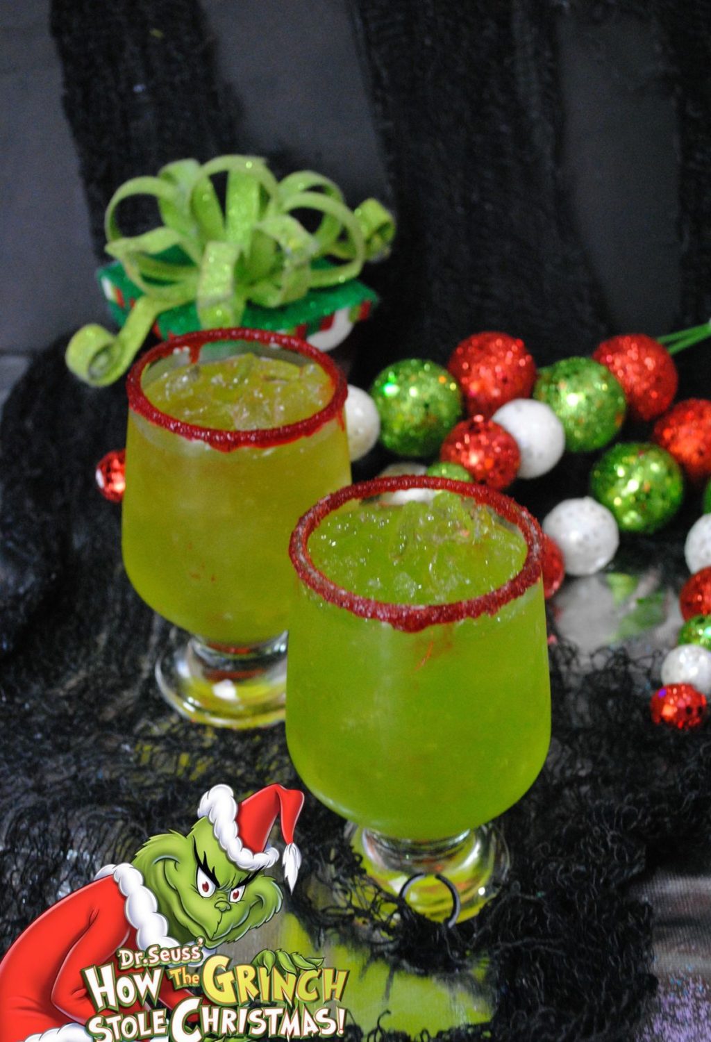 Two glasses of green drink with santa claus decorations.